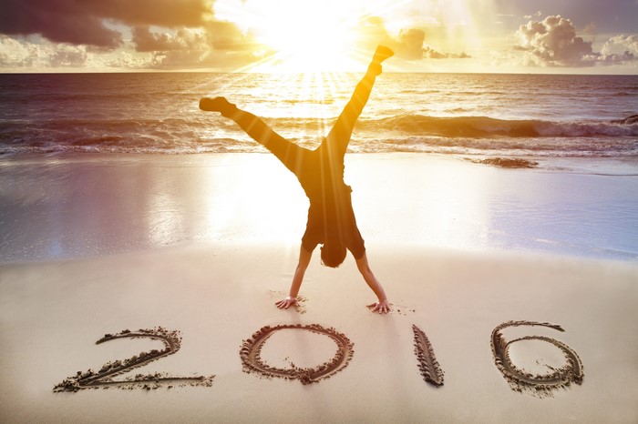 Person doing a handstand on a beach with '2016' written in the sand