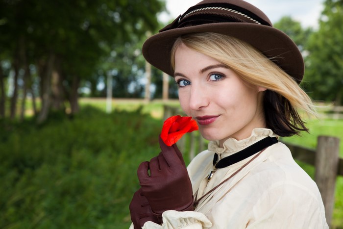 Blonde girl in a hat holding a red flower