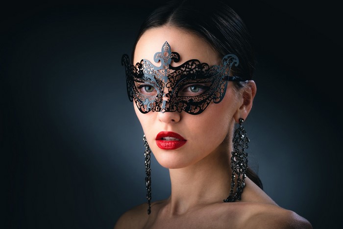 Woman wearing a black masquerade mask and earrings