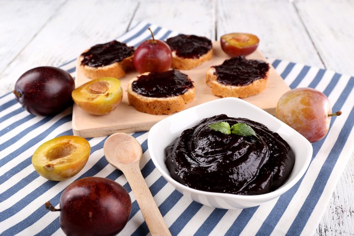 Plum jam on bread with plums and spoon