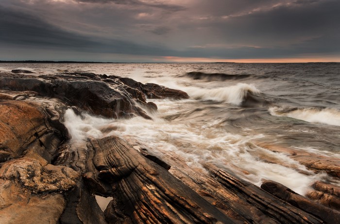 Waves crashing on rocky shore at sunset in Varmland, Sweden