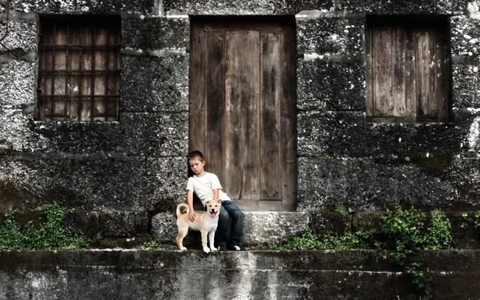 Boy and dog sitting by a wooden door
