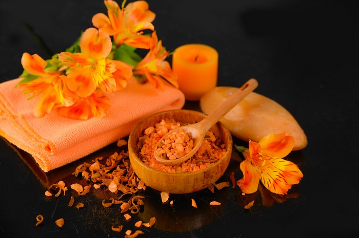 Spa setting with orange flowers, candle, and bath salts
