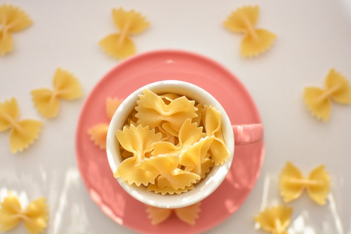 Farfalle pasta in a cup on a pink plate