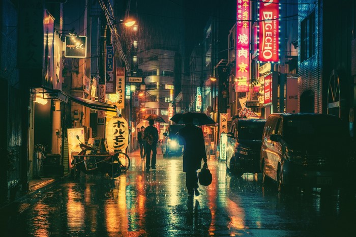 Rainy night street with neon signs and people