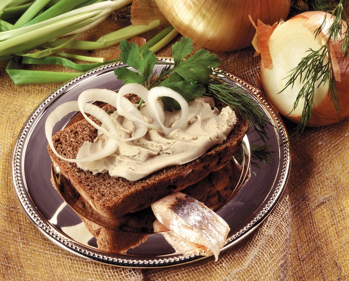 Sandwich with spread, onion, and herring on a plate