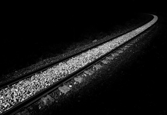 Railroad tracks curving into darkness