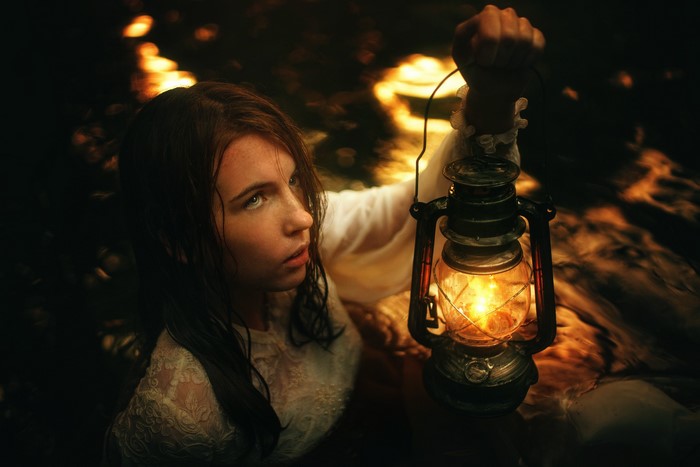 Woman holding a kerosene lamp in water