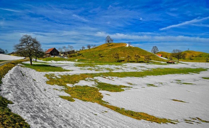 Spring landscape with melting snow and farm buildings
