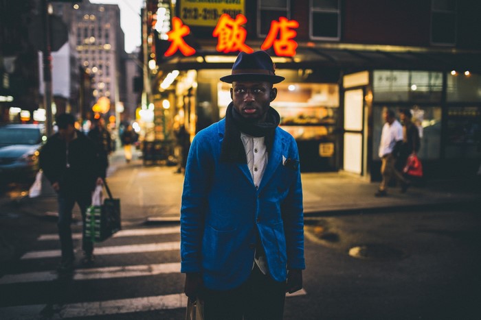 Man in blue jacket and hat on city street