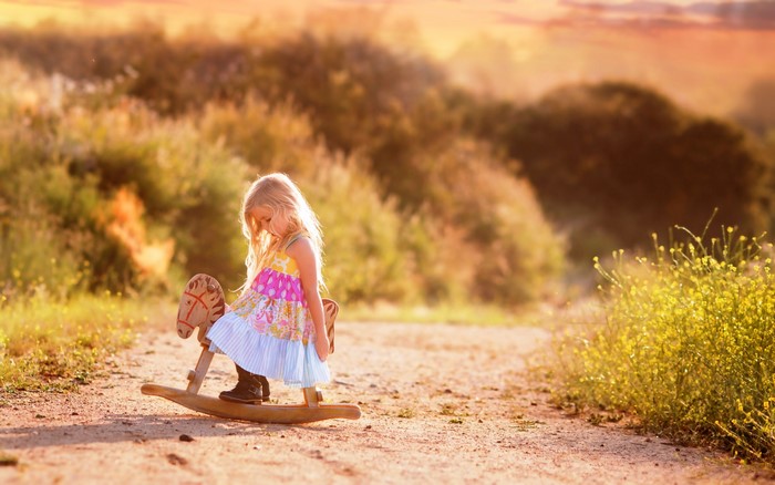 Girl on a rocking horse on a dirt road