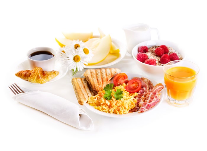 Breakfast with coffee, croissant, eggs, bacon, toast, fruit, and juice