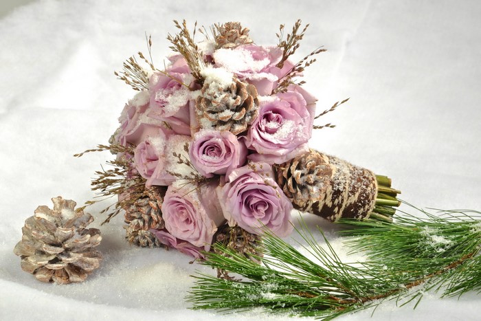 Winter bouquet of pink roses with pine cones and snow