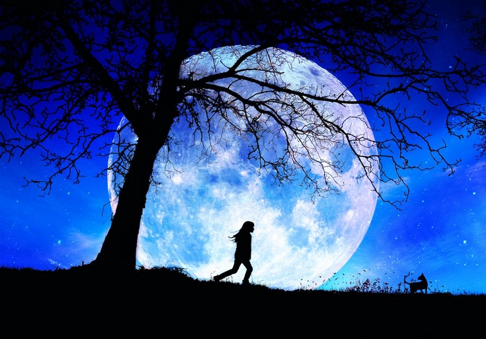 Silhouette of a girl running under a large moon