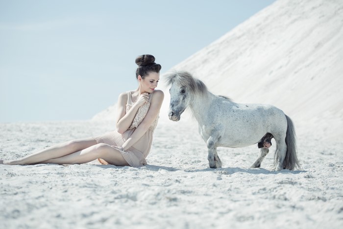 Woman and miniature horse on sand
