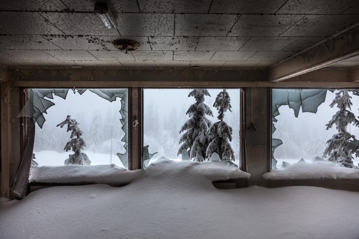 Abandoned room with broken windows and snow