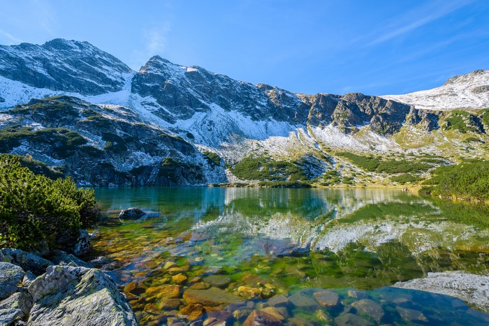 Mountain lake with snow-capped peaks and rocky shore