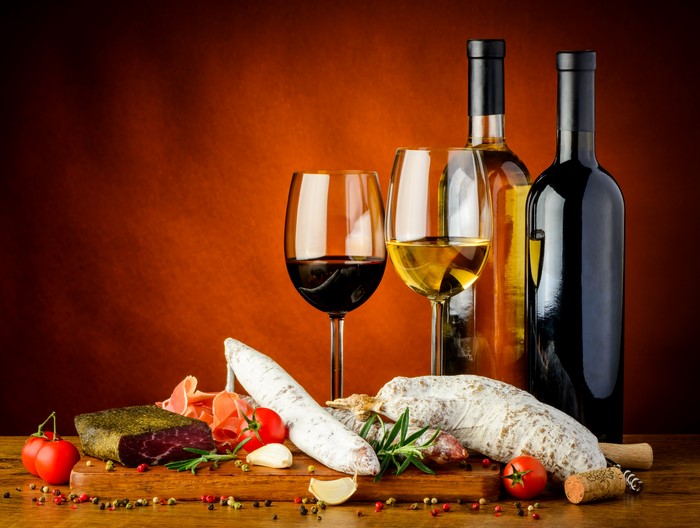 Wine bottles and glasses with charcuterie and tomatoes