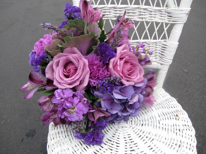 Purple and pink floral bouquet on a white wicker chair