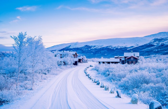 Winter road through snow-covered landscape with houses