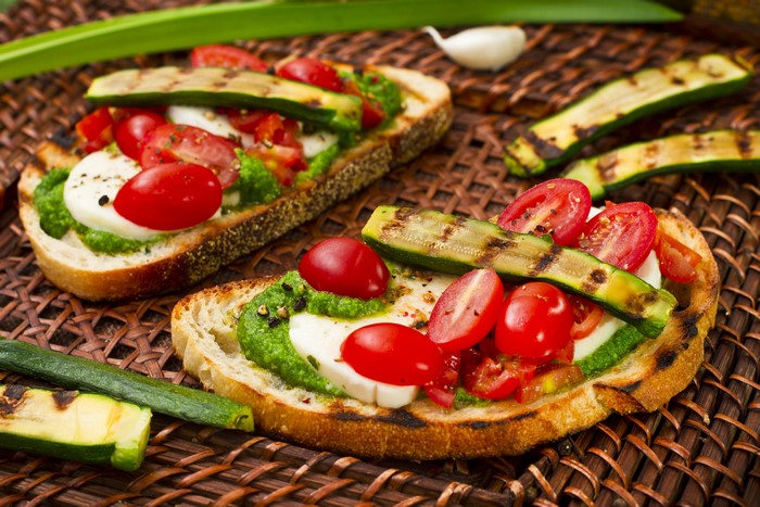 Bruschetta with grilled zucchini, tomatoes, mozzarella, and pesto
