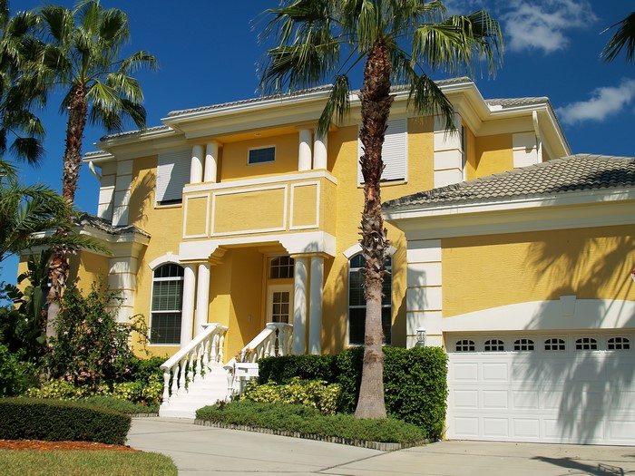 Yellow mansion with palm trees and white garage door