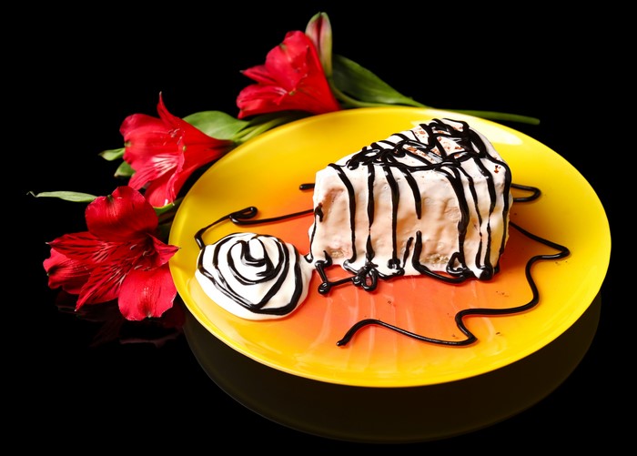 Slice of cake with chocolate drizzle and alstroemeria flowers