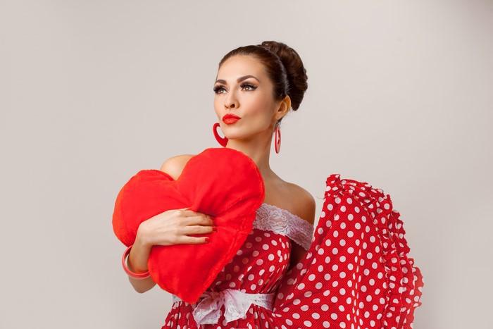 Woman in red polka dot dress holding a heart
