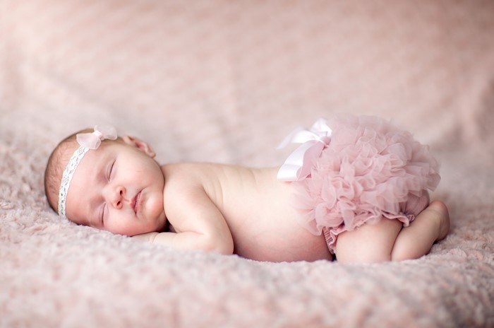 Newborn baby girl sleeping on pink blanket
