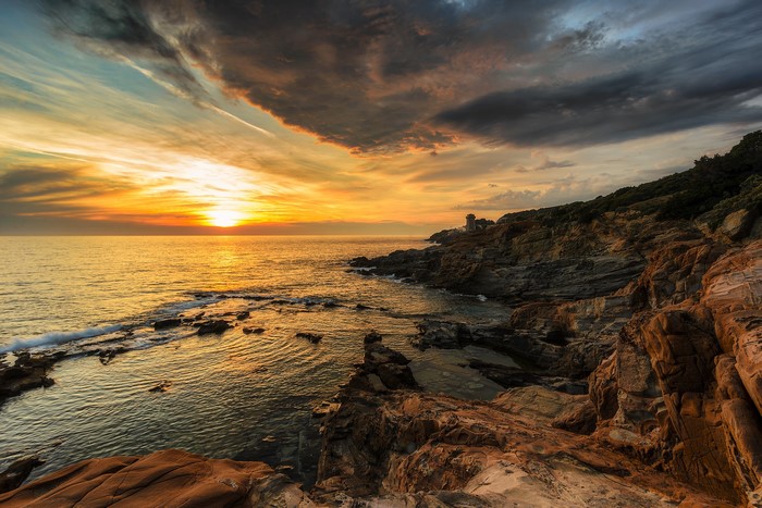 Sunset over the rocky coast of Italy with clouds