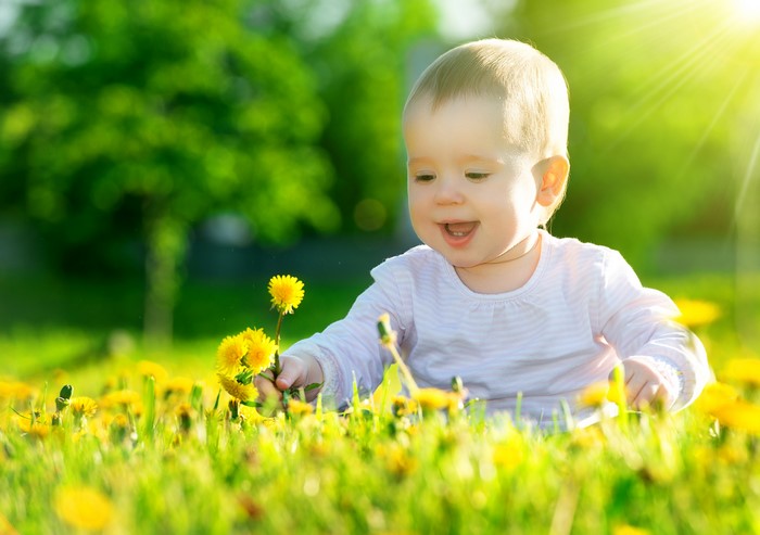 Baby smiling in a field of dandelions