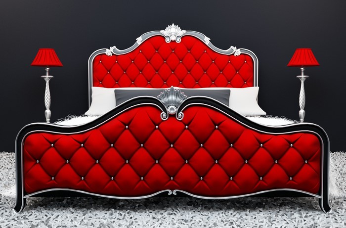 Red tufted bed with silver accents and red lamps