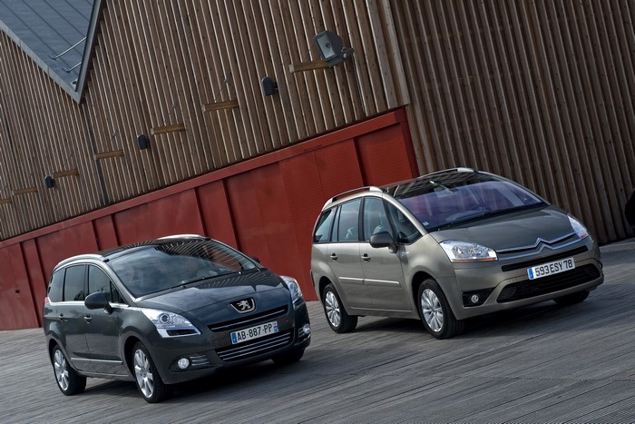 Two metallic MPVs parked on a wooden deck