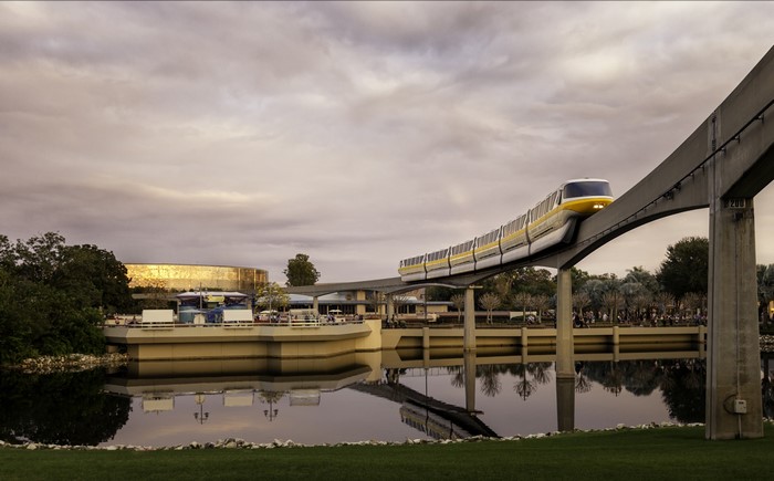 Monorail train on elevated track over water with Epcot in background