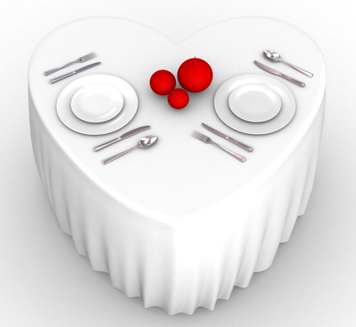 Heart-shaped table setting with red candles and place settings