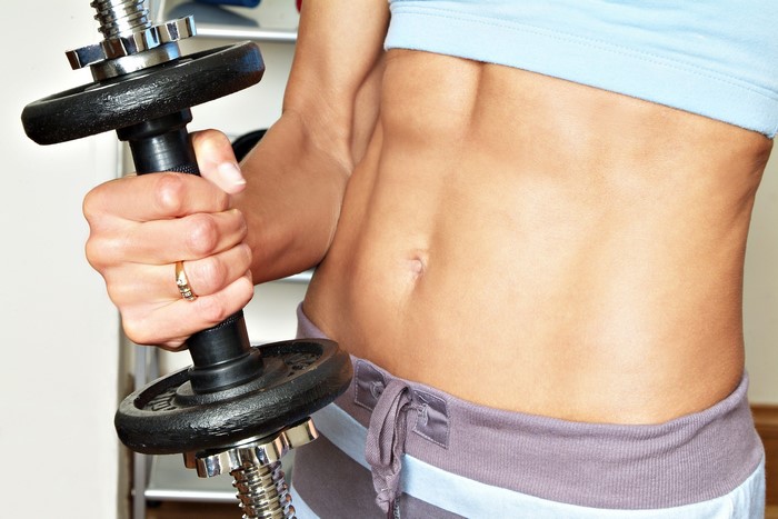 Woman holding a dumbbell, showing abs