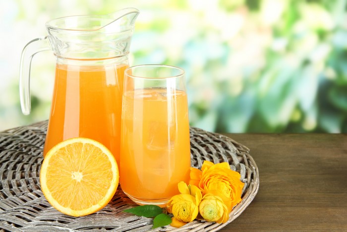 Orange Juice in Pitcher and Glass with Orange Slice and Flowers