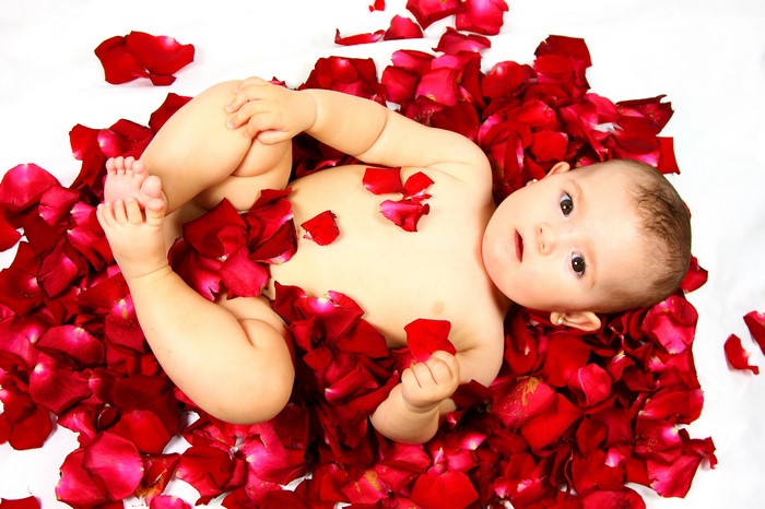 Baby lying in red rose petals