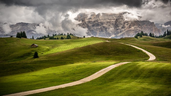 Winding road through green hills in the Dolomites, Italy