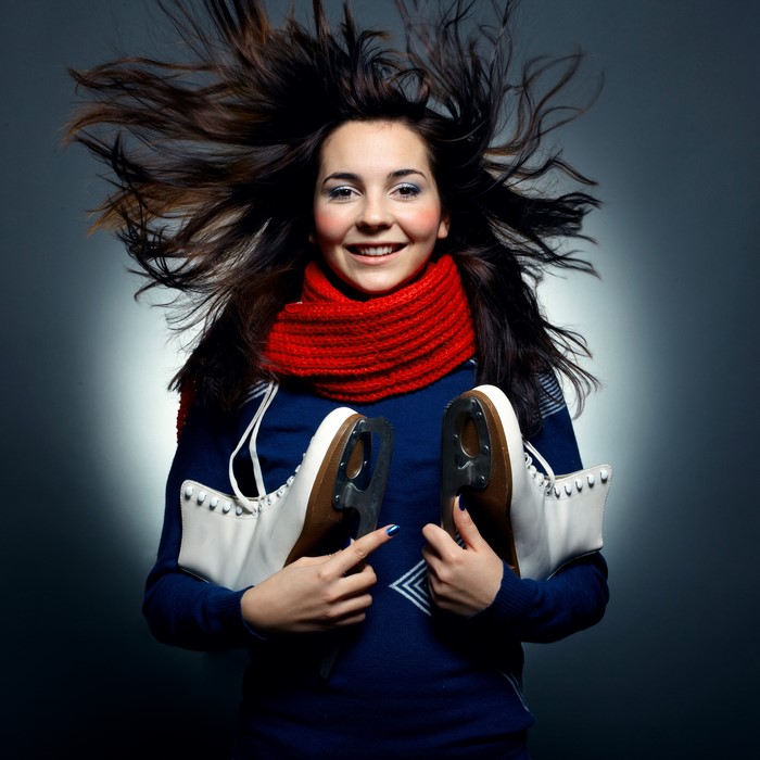 Young woman with ice skates and red scarf