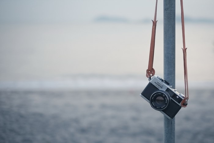 Olympus retro camera hanging on a pole at the beach