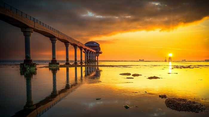 Pier and lighthouse at sunset over the sea