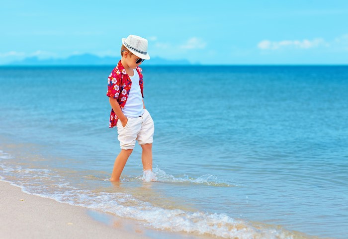 Boy in Hawaiian shirt and hat on beach