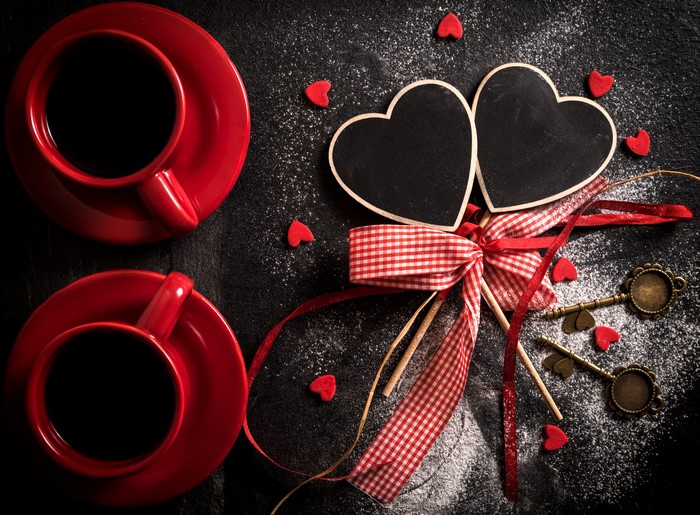 Two red coffee cups with heart decorations and keys