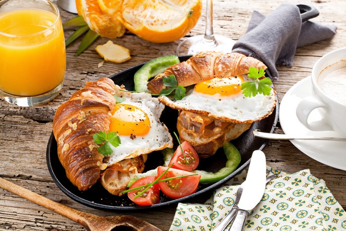 Croissant breakfast with fried eggs, juice, and coffee