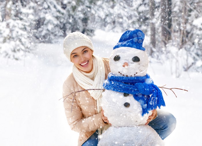 Woman building a snowman in a snowy forest
