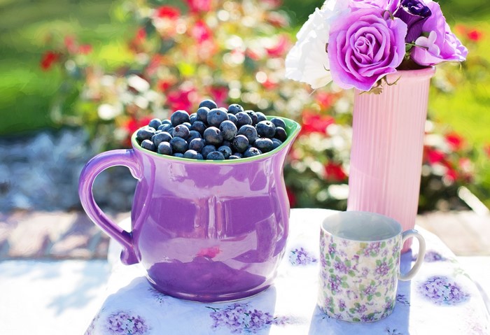 Blueberries in a purple jug with flowers