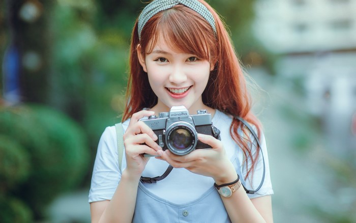 Asian girl with brown hair holding a Minolta camera