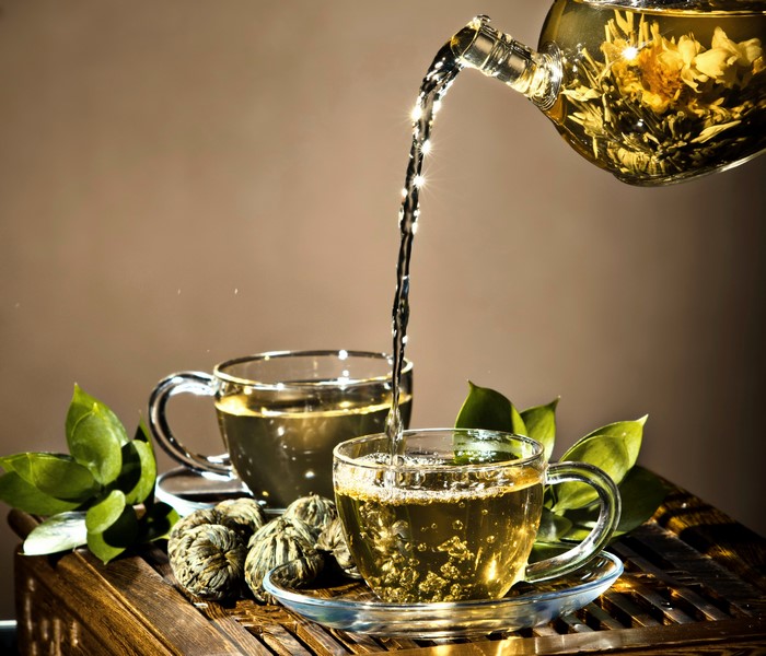 Tea being poured into a cup with tea leaves