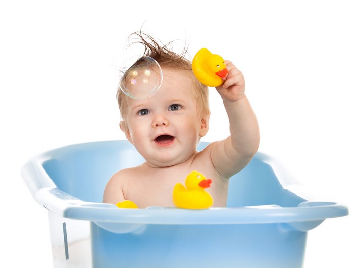 Baby playing with rubber ducks in a bathtub